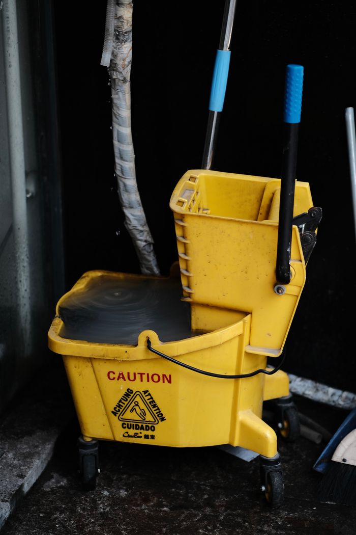 contact-img Close-up of a yellow mop bucket with caution sign, ideal for cleaning and maintenance themes.