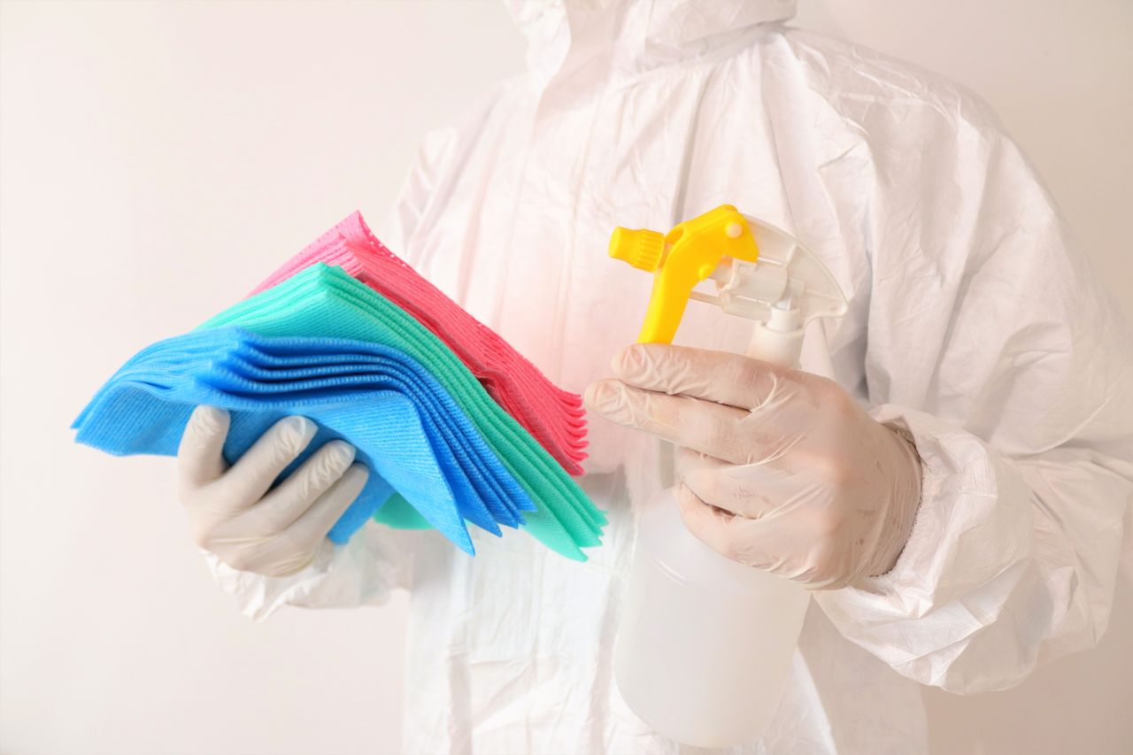 services-img Individual in PPE holds cleaning cloths and spray bottle, ensuring hygiene and safety.